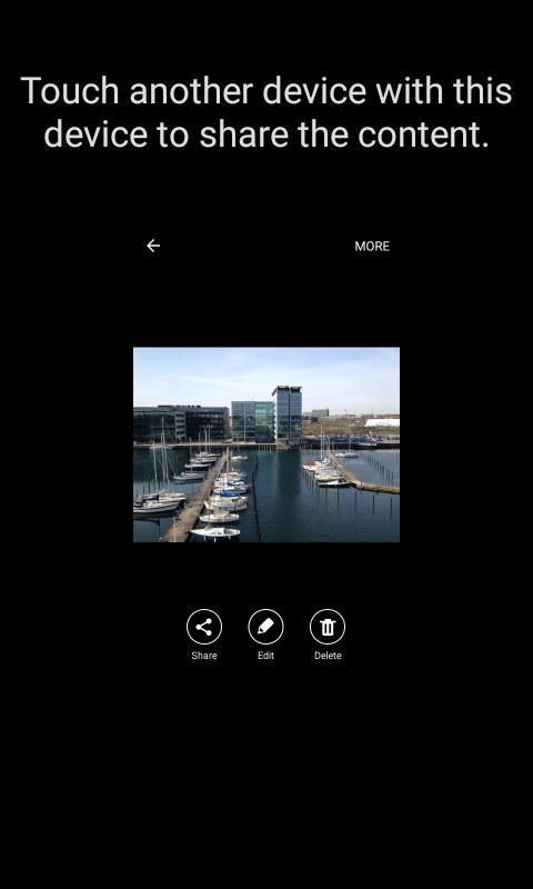 Hold the back of your phone close to back of the receiving device. Press Touch another device with this device to share the content. and wait while the file is transferred.
